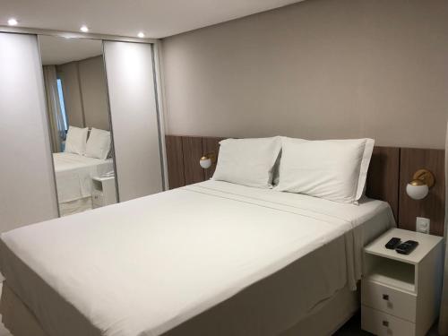 a bedroom with a large white bed and a mirror at Flat Beira Mar de Tambaú apto 206 in João Pessoa