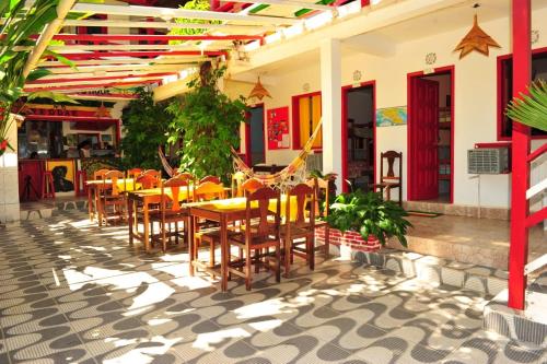 un restaurante con mesas y sillas en un patio en Papagaio Hostel & Pousada, en Morro de São Paulo