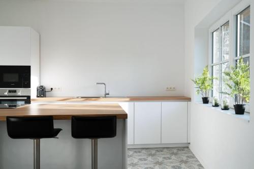 a kitchen with white cabinets and a counter with stools at Gîtes des Remparts in Philippeville