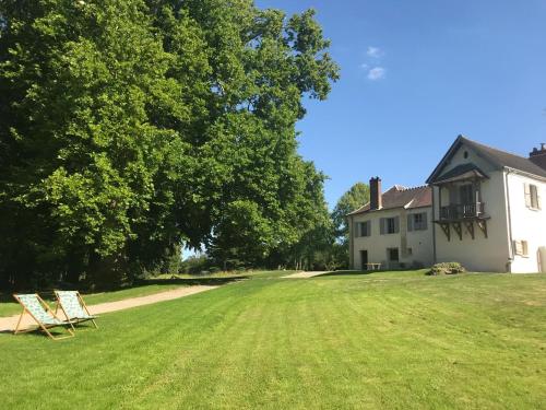 a yard with two lawn chairs in front of a house at Domaine du Plessis in Le Plessis-Luzarches
