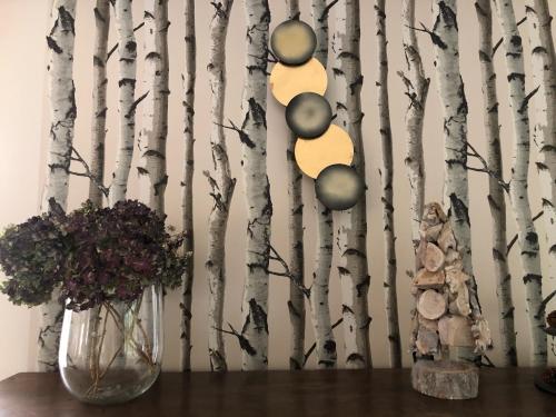 a table with a vase of flowers and a tree mural at Domaine du Plessis in Le Plessis-Luzarches