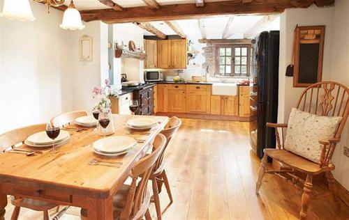 a kitchen with a wooden table with chairs and a dining room at Host & Stay - Tregaer Mill Barn in Dingestow