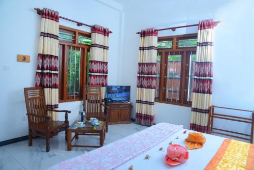 a bedroom with a bed and chairs and windows at Gold sand Resort in Bentota