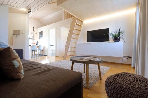 a living room with a couch and a tv and a table at Neuhof Gäste-& Schokohaus in Appenzell