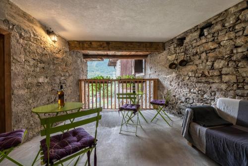 a room with a table and chairs and a stone wall at Agriturismo Al Gallo Nero Lilla in Tenno