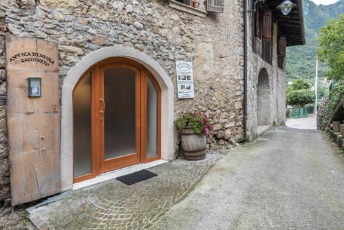 a stone building with a wooden door on a street at Agriturismo Al Gallo Nero Lilla in Tenno