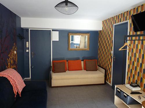 um quarto com um sofá com almofadas laranja em LE LOGIS DU PALAIS em Marselha