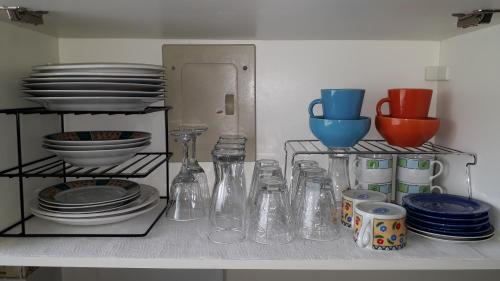 a shelf with glass vases and plates on it at Lindo apartamento em Frente ao mar na Ilha Comprida in Ilha Comprida