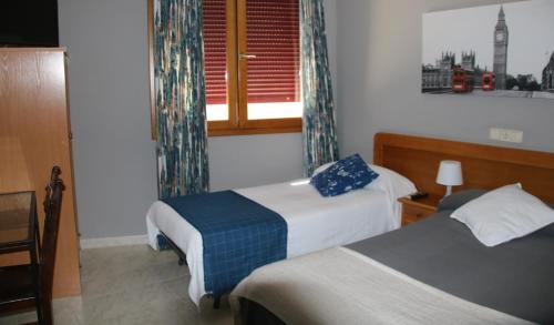 a hotel room with two beds and a window at HOSTAL BURGALES in Milagro