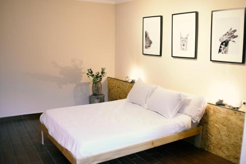 uma cama com lençóis brancos e almofadas num quarto em Azul añil EL PATIO Casa rural en Alameda em Alameda