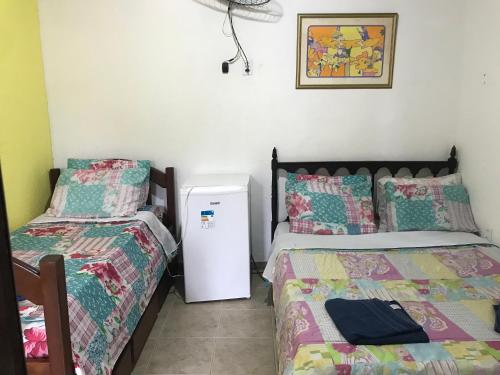 a room with two beds and a refrigerator at Solar Glorinha in Búzios