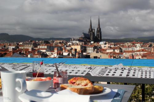 a table with a plate of food and a view of a city at Hotel Litteraire Alexandre Vialatte, BW Signature Collection in Clermont-Ferrand