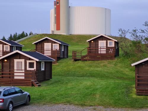 a group of cabins on a hill with a car at Höfn Cottages in Höfn