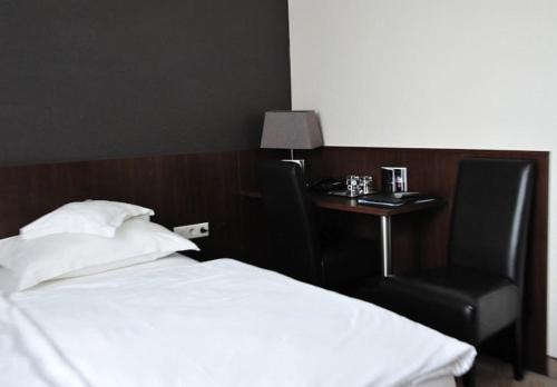a bedroom with a bed and a table and a chair at Hotel Lindenhof in Düsseldorf