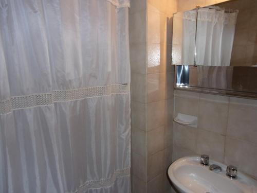 y baño con cortina de ducha y lavamanos. en Departamento Costanera Bariloche en San Carlos de Bariloche