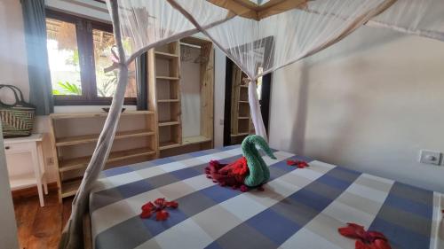 a toy dinosaur sitting on a bed in a bedroom at Salama & Mbuyuni Bungalows in Matemwe