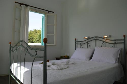 a bedroom with a bed with white sheets and a window at Aegean Village in Parikia
