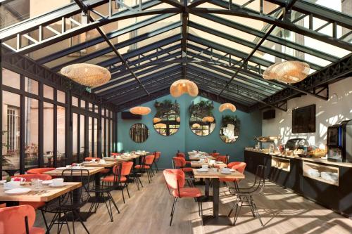 un restaurant avec des tables, des chaises et des fenêtres dans l'établissement Appartements des Ducs, à Dijon