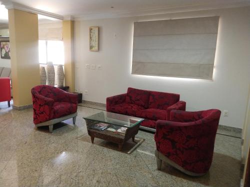 a living room with two red chairs and a table at Crystal Plaza Hotel Marista in Goiânia