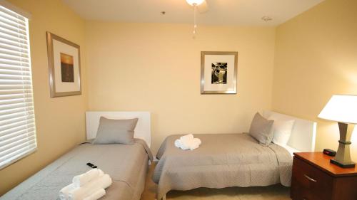 a bedroom with two beds and a lamp and a window at John's Pass Hotel - Fully Remote Check In in St Pete Beach