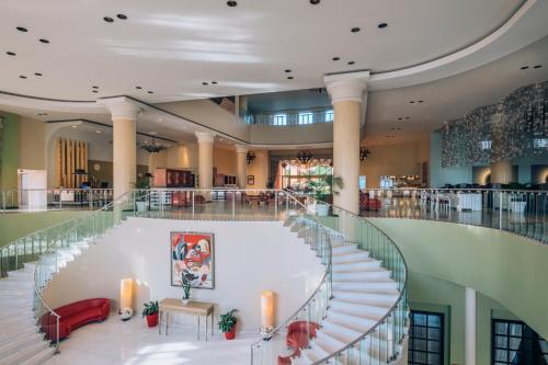 a large lobby with a staircase with red chairs at Iberostar Selection Rose Hall Suites - All Inclusive in Montego Bay