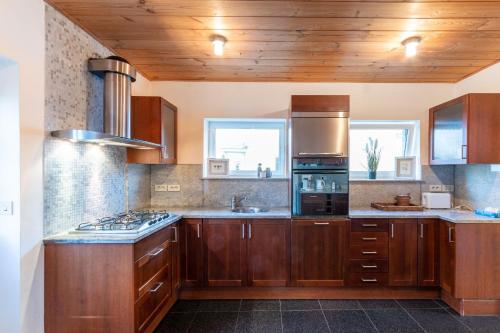 een keuken met houten kasten en een fornuis met oven bij Villa Mercator - Nieuwpoort-Bad in Nieuwpoort