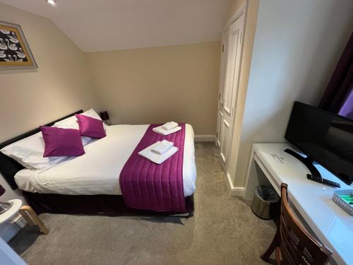 a hotel room with a bed with pink pillows at The Swan @Old Stratford in Milton Keynes