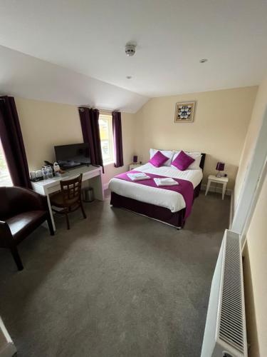 a bedroom with a bed with pink pillows and a desk at The Swan @Old Stratford in Milton Keynes
