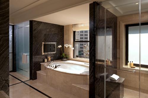 a bathroom with a tub and a tv and a window at The Peninsula New York in New York