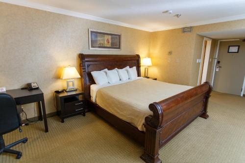 a hotel room with a large bed and a desk at The George Dawson Inn & Conference Centre in Dawson Creek