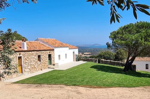 a house with a grassy yard next to a building at Lettu di Ita - Spectacular Gallura Stazzu with sea view and pool in Santa Teresa Gallura