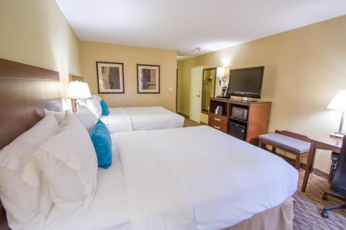 a hotel room with two beds and a flat screen tv at Holiday Inn Bloomington Airport South-Mall Area by IHG in Bloomington