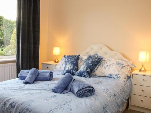 a bed with blue and white pillows and a window at Greenacres in Kimbolton