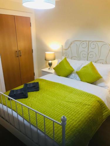 a bedroom with a large bed with a green blanket at ochiltree apartment in Glasgow