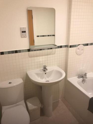 uma casa de banho com um lavatório, um WC e um espelho. em ochiltree apartment em Glasgow
