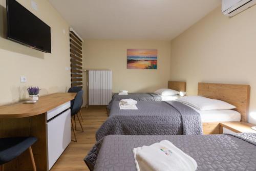 a hotel room with two beds and a flat screen tv at Sobe Mili Ozren in Doboj