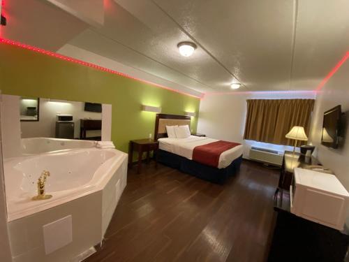 Habitación de hotel con bañera y cama en Skylight Inn Willoughby - Cleveland Mentor, en Willoughby