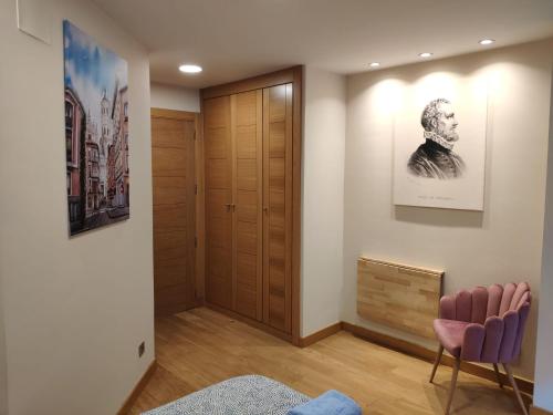 a hallway with a chair and a picture of a man at Apartamento Juan de Herrera VUT47168 in Valladolid