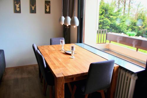 a dining room table with chairs and a large window at Harzbutze 60 in Sankt Andreasberg