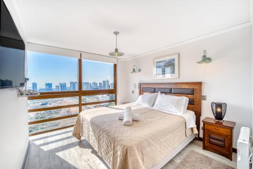 ein Schlafzimmer mit einem Bett und einem großen Fenster in der Unterkunft Sunny Side 3BR W/ View, Parking, Pool & Gym in Viña del Mar