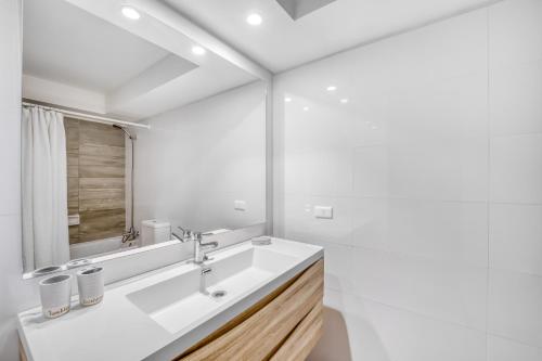 ein weißes Badezimmer mit Waschbecken und Spiegel in der Unterkunft Sunny Side 3BR W/ View, Parking, Pool & Gym in Viña del Mar