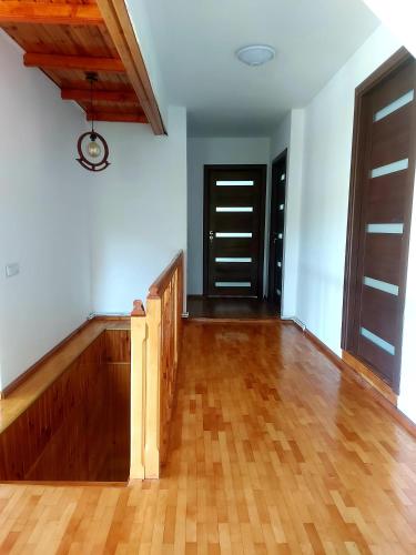 an empty room with wooden floors and doors at Pensiunea Poiana Luminoasă in Bughea de Jos