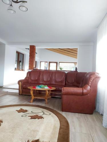 a living room with a brown leather couch and a table at Pensiunea Poiana Luminoasă in Bughea de Jos