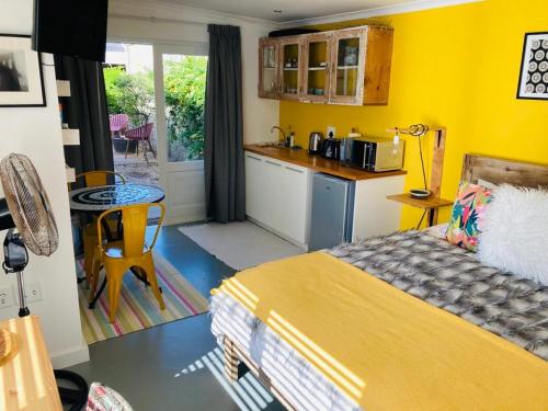 um quarto amarelo com uma cama e uma cozinha em Modern studio apartment na Cidade do Cabo