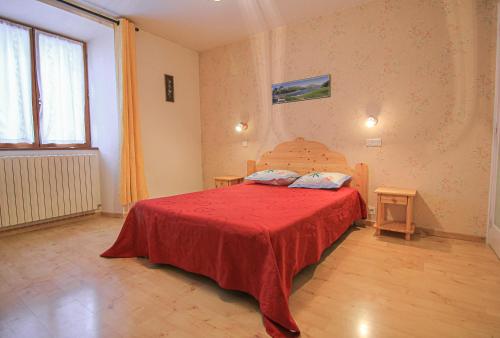 - une chambre avec un lit avec un couvre-lit rouge et 2 tables dans l'établissement Le Lys orangé, à Lanslebourg-Mont-Cenis