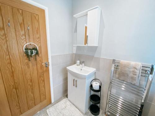 a white bathroom with a sink and a mirror at LITTLE RED HOLIDAY HOME - 2 Bed House with Free Parking within West Yorkshire, local access to the Peak District in Halifax