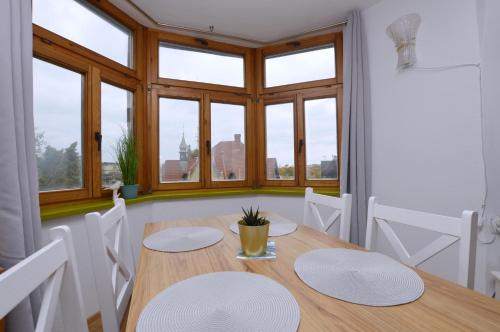 jadalnia ze stołem, krzesłami i oknami w obiekcie Piękny Apartament 3city z Balkonem w Centrum Sopotu by Noclegi Renters w mieście Sopot
