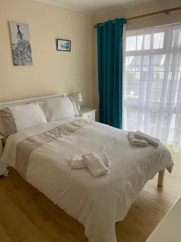 1 dormitorio con 1 cama blanca grande y cortinas azules en Cozy seaside home,3 minute walk to village/beach, en Lahinch