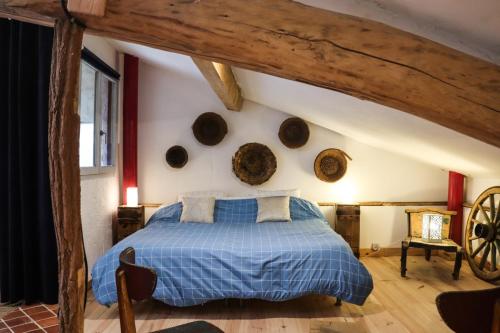 - une chambre avec un lit bleu et des poutres en bois dans l'établissement Le Moulin de Chamambard, à Saint-Denis-lès-Bourg