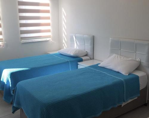 two beds with blue sheets in a room with windows at Fabulous 3 bedroom Apartment in Dalyan with pool in Dalyan